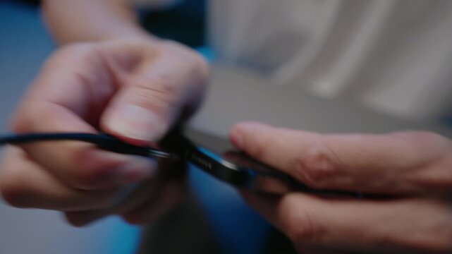 Close-up view of male hands unplugging black USB C cable from modern smartphone. Concept of port, device connecting for charging, data transfer, technology and energy. Shooting in slow motion.