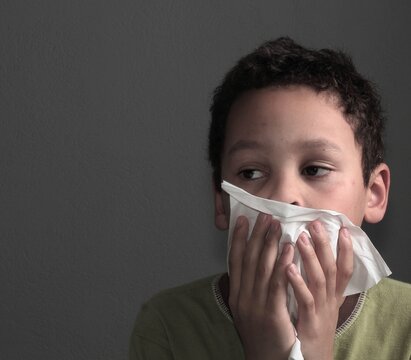 flu epidemic with child blowing nose after catching a cold with people on dark background stock image stock photo