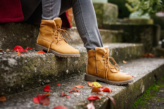 Beige shoes. Woman with leather ankle boots sitting on stairs in city. Autumn fashion street style