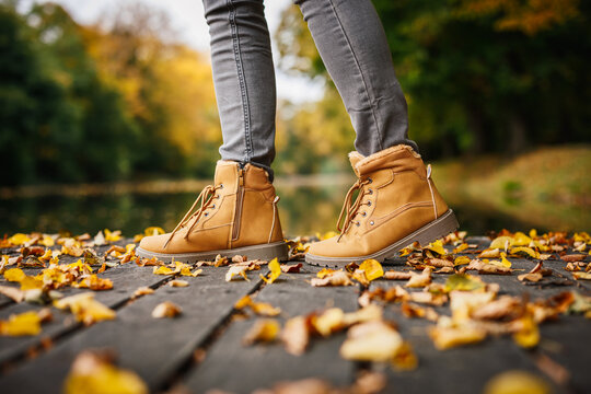 Leather ankle boots. Woman in beige shoe standing in public park. Autumn fashion style