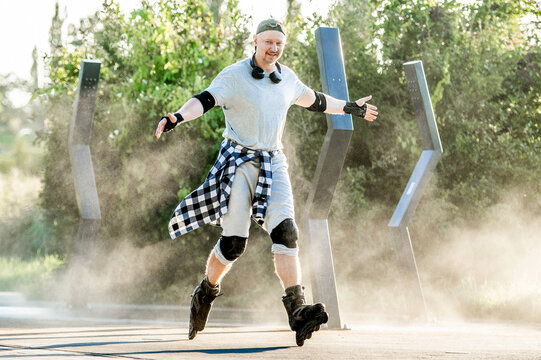 Man in protective gear balances on rollerblades while moving along a dusty park trail outdoors