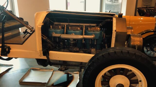 Detailed shot of a rare antique vintage automobile chassis and exposed engine block on exhibition inside a classic car museum, showcasing early automotive engineering 