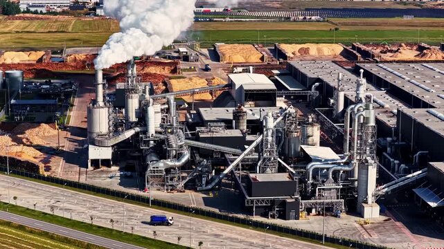 Aerial view of an industrial wood processing facility with smoke stacks and piles of wood chips in Suwalki, Podlaskie Voivodeship, Poland.