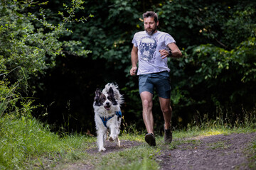 Naklejka premium happy man and dog running in forest