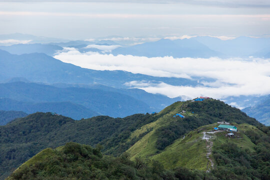 View of the Mardi Himal Trek landscape featuring mountain ridges, lush green slopes, and small lodges nestled among the clouds in Pokhara, Gandaki Province, Nepal.