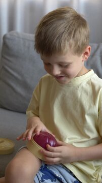 Boy opens toy packaging to discover a pink dumpling toy. Hands-on unboxing captures curiosity, excitement and sensory play, highlighting the colorful product and playful childhood activity.