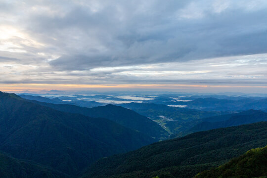 View of the Mardi Himal Trek landscape with rolling mountain ranges, lush green slopes, and a cloudy sky at dawn in Pokhara, Gandaki Province, Nepal.