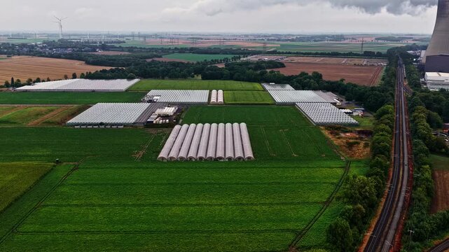 Aerial view of RWE Power AG power plant Niederaussem surrounded by greenhouses and agricultural fields in Bergheim, Nordrhein-Westfalen, Germany.