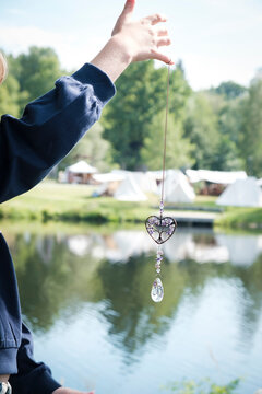 Hand holding crystal sun catcher against blurred lake background