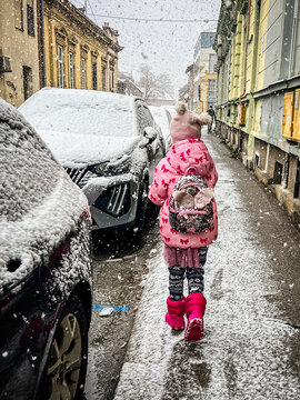 Young traveler walking beside snowy streets and buildings