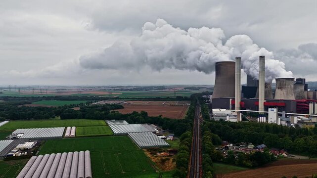 Aerial view of the RWE Power AG power plant Niederaussem with surrounding greenhouses and industrial infrastructure in Bergheim, Nordrhein-Westfalen, Germany.