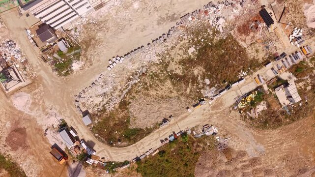 Aerial Top Down View of Construction Site Ground with Cranes and Rooftop Solar Panels Nearby
