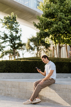 Man enjoying a sunny day while checking his phone in a lush outdoor setting