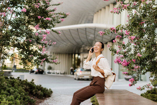 Korean woman enjoying a sunny day while chatting on the phone outdoors