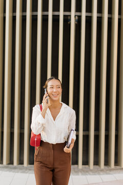 Korean woman smiles while talking on phone during a busy day in the city