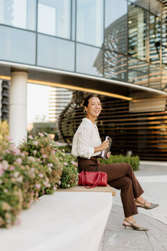 Enjoying a sunny afternoon in the city with a smile and a red handbag