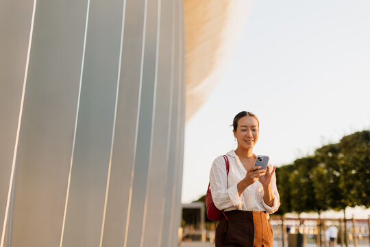 Korean woman enjoys a sunny afternoon while texting on her smartphone