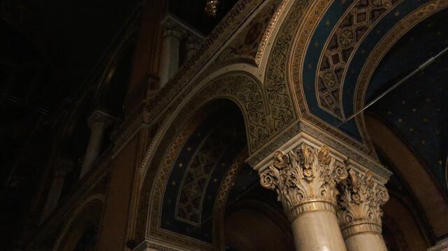 Panning interior shot of an ornate Greek Orthodox cathedral showing decorated vaulted ceilings, intricate golden arches, marble Corinthian columns, chandeliers, 
