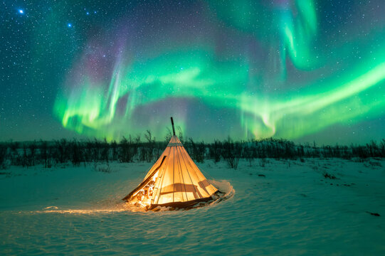 Glowing tent in a winter landscape under the beautiful Aurora Borealis Northern Lights display