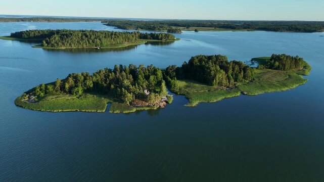 Drone flight above a picturesque Finnish Gulf archipelago revealing rocky islands narrow channels calm blue water and untouched northern coastal nature