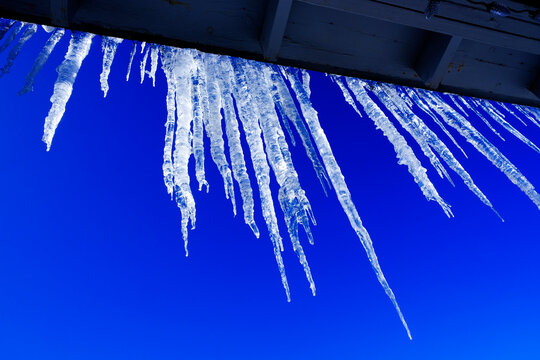 Icicles Hanging from Roof in Winter Blue Sky