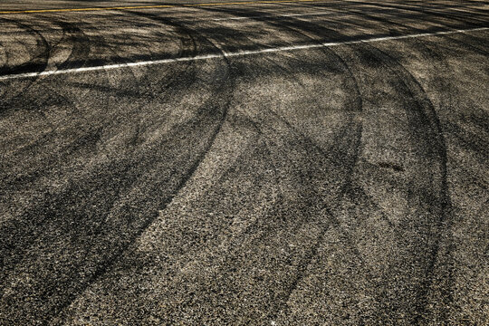 Dark Tire Tracks Burning Rubber on Road or Street with Painted Lines Showing Traffic Flow Peeling Out with Car Skid Marks