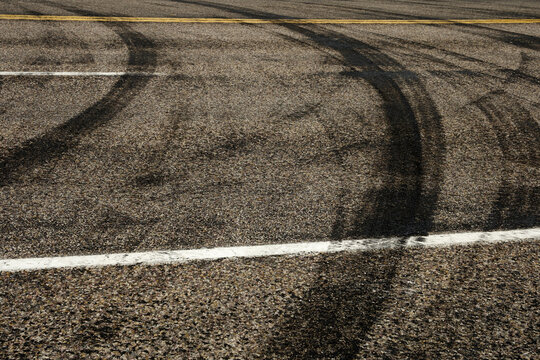 Dark Tire Tracks Burning Rubber on Road or Street with Painted Lines Showing Traffic Flow Peeling Out with Car Skid Marks