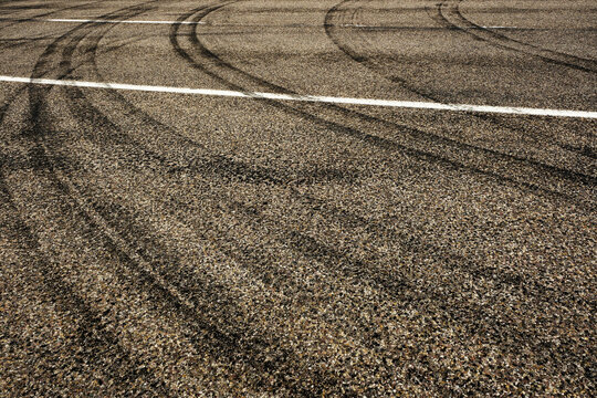Dark Tire Tracks Burning Rubber on Road or Street with Painted Lines Showing Traffic Flow Peeling Out with Car Skid Marks