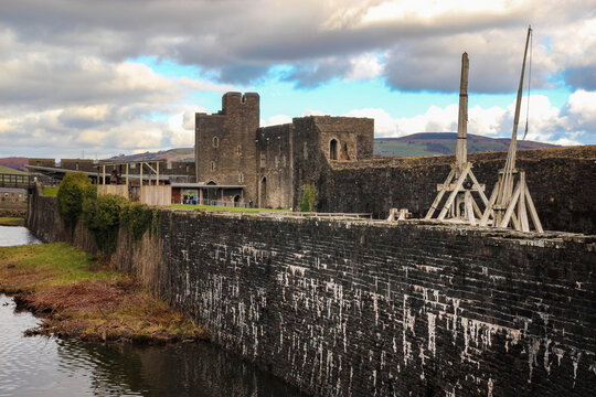 Reconstructed medieval siege weapons standing beside high stone walls at Caerphilly Castle South Wales UK