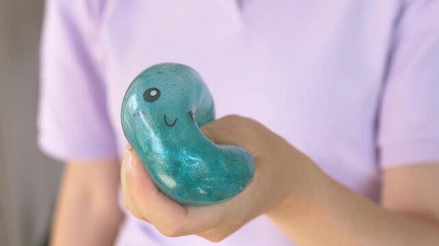 Hand cradles turquoise squishy dumpling toy against body closeup showing cute smiling face clearly. Soft round eyes and curved mouth complete this cuddly kawaii character gift for comfort 