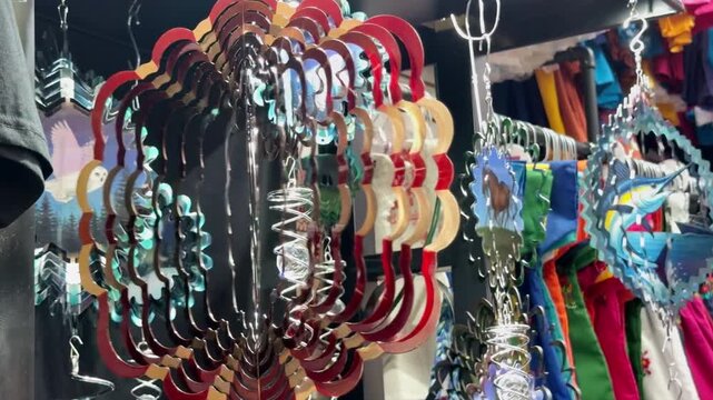 Vibrant kinetic wind spinners hang in a bustling market stall