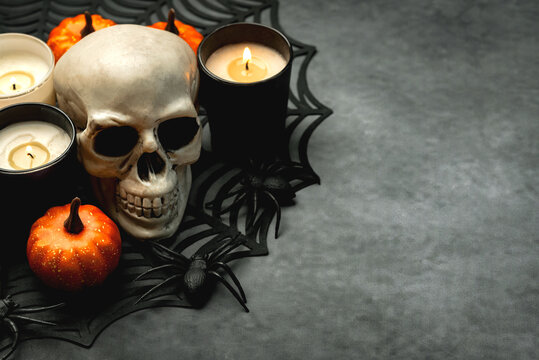 Closeup of scary evil skeleton skull with candles and Halloween pumpkins with copy space for text. Halloween concept background