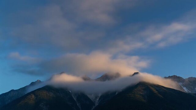 Misty mountain peaks illuminated by golden hour light during dawn or dusk