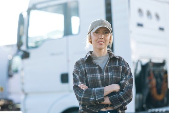 Woman truck driver with arms crossed in front of semi-truck