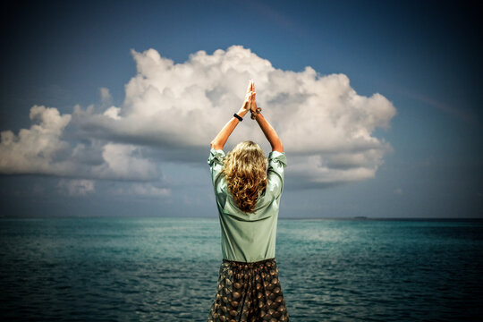 woman doing yoga against sunset cloud over the ocean