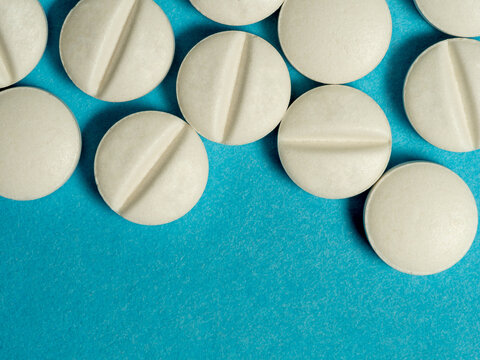 Close-Up of White Round Tablets With Imprint 289 on Blue Background, Medical Pills Concept