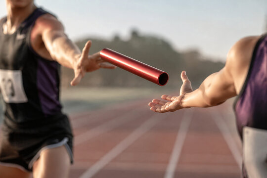 Relay baton in mid-air transfer between two blurred runners on a track.