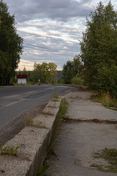 Perspective view of an empty asphalt road and concrete sidewalk in the industrial zone of a provincial Russian town. Northern urban landscape.