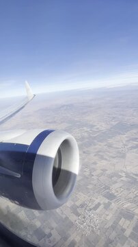 View from airplane window with jet engine and landscape below