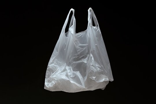 Transparent plastic shopping bag with handles, suspended against a dark background