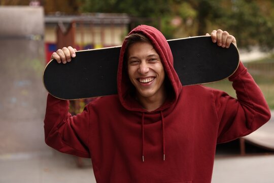 Happy man with skateboard in skate park