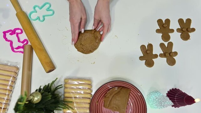 Beautiful hands knead dough while surrounded by playful gingerbread cookies. A Christmas tree sparkles, adding charm to this delightful baking scene filled with holiday spirit.