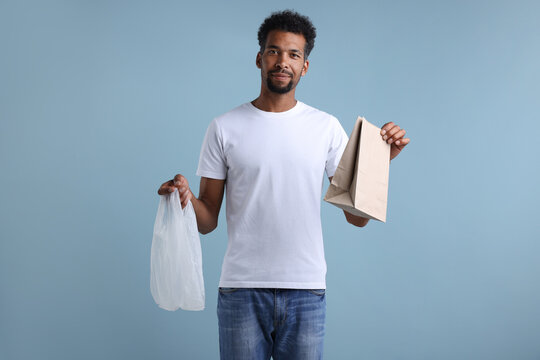 Man choosing between plastic and paper bag on light blue background