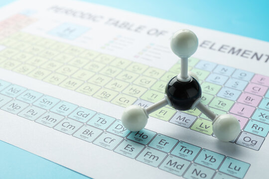 Chemical model of molecule and periodic table on light blue background, closeup. Space for text