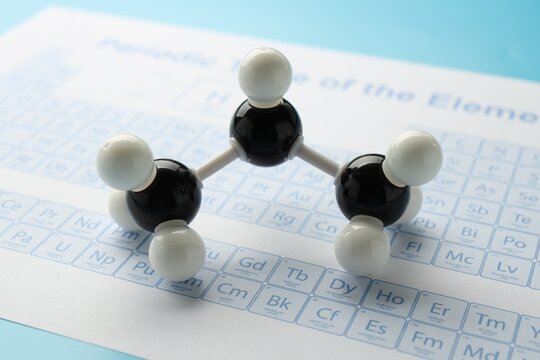 Chemical model of molecule and periodic table on light blue background, closeup