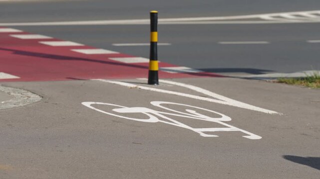 Cyclist riding along designated bike lane in modern city, close-up view of bicycle crossing white bicycle lane markings and road symbols, urban cycling infrastructure and sustainable transportation