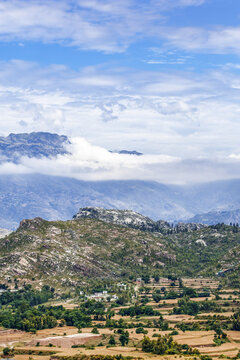 View of the mountainous landscape with terraced fields, rocky slopes, and lush greenery under a cloudy sky in Lower Dir, Khyber Pakhtunkhwa, Pakistan.