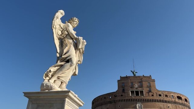 Low angle shot of Bernini angel statue on Ponte Sant&rsquo;Angelo with blue sky Rome
