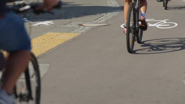 Cyclists riding along designated bike lane in modern city, close-up view of bicycles crossing white bicycle lane markings and road symbols, urban cycling infrastructure and sustainable transportation