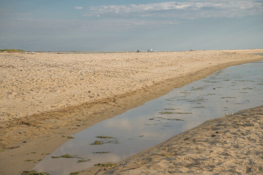 View of a sandy beach with a shallow tidal pool and calm waters under a clear blue sky, Morondava, Menabe, Madagascar.